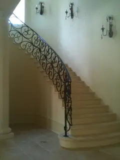 Curved staircase beside a pale wall.