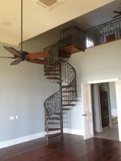 Spiral staircase beside a tall window.